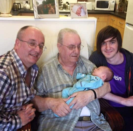 Four generations: my father, Grandy holding baby Alex, and me, with Grandy's own father in a photograph behind, making five